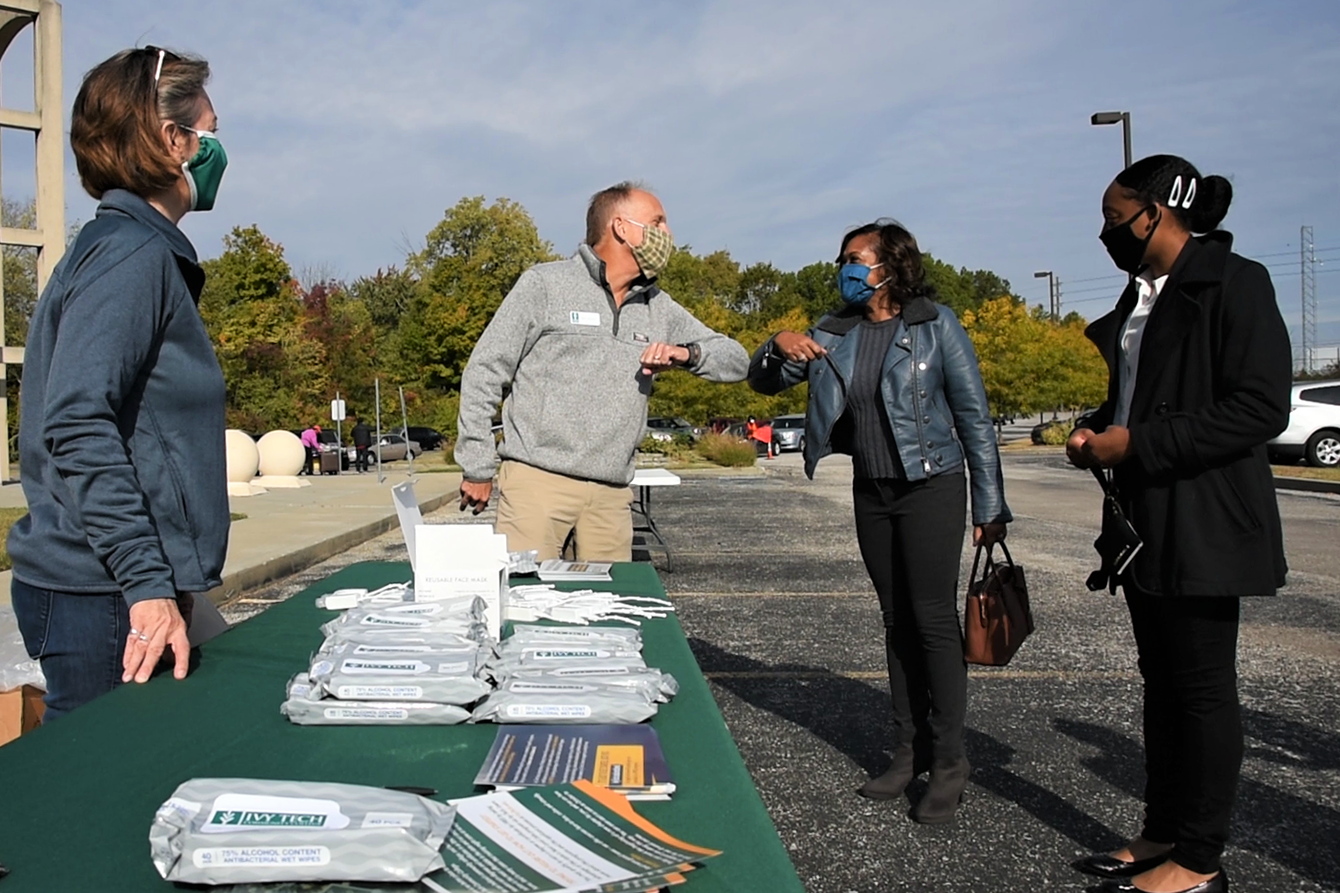 Chris Lowrey, Ivy Tech senior vice president of workforce alignment, does an elbow bump in greeting to someone visiting the booth for job training information. Photo credit, Justin Hicks for IPB News.