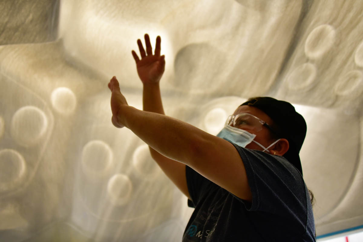 Mang stands inside an overturned spa shell, demonstrating how workers will inspect the newly-molded shell for small imperfections like cracks or dimples. Image credit: Justin Hicks, IPB News