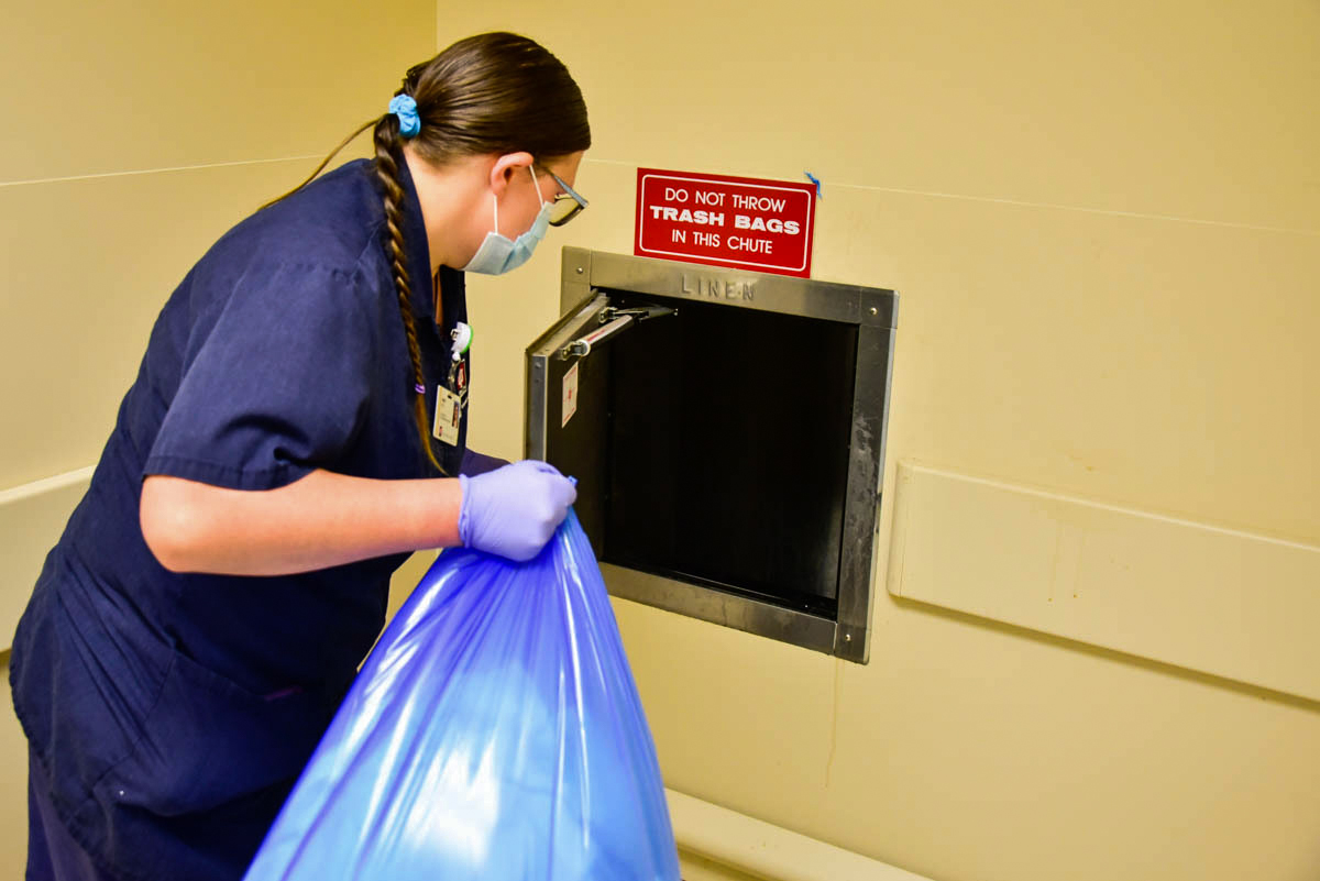 Beck prepares to toss a bag of linens down a chute that leads from the eighth floor of the hospital to a laundry room in the basement. Image credit: Justin Hicks, IPB News