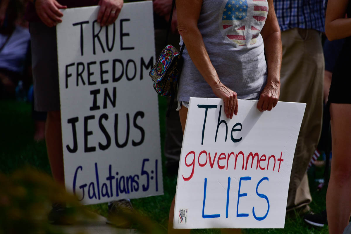 Protesters held signs at a rally against vaccine mandates, touting religious freedom over government control. Two signs at a Statehouse protest of vaccine mandates. One reads, TRUE FREEDOM IN JESUS Galatians 5:1. The other reads, The government lies. Image credit: Justin Hicks, IPB News