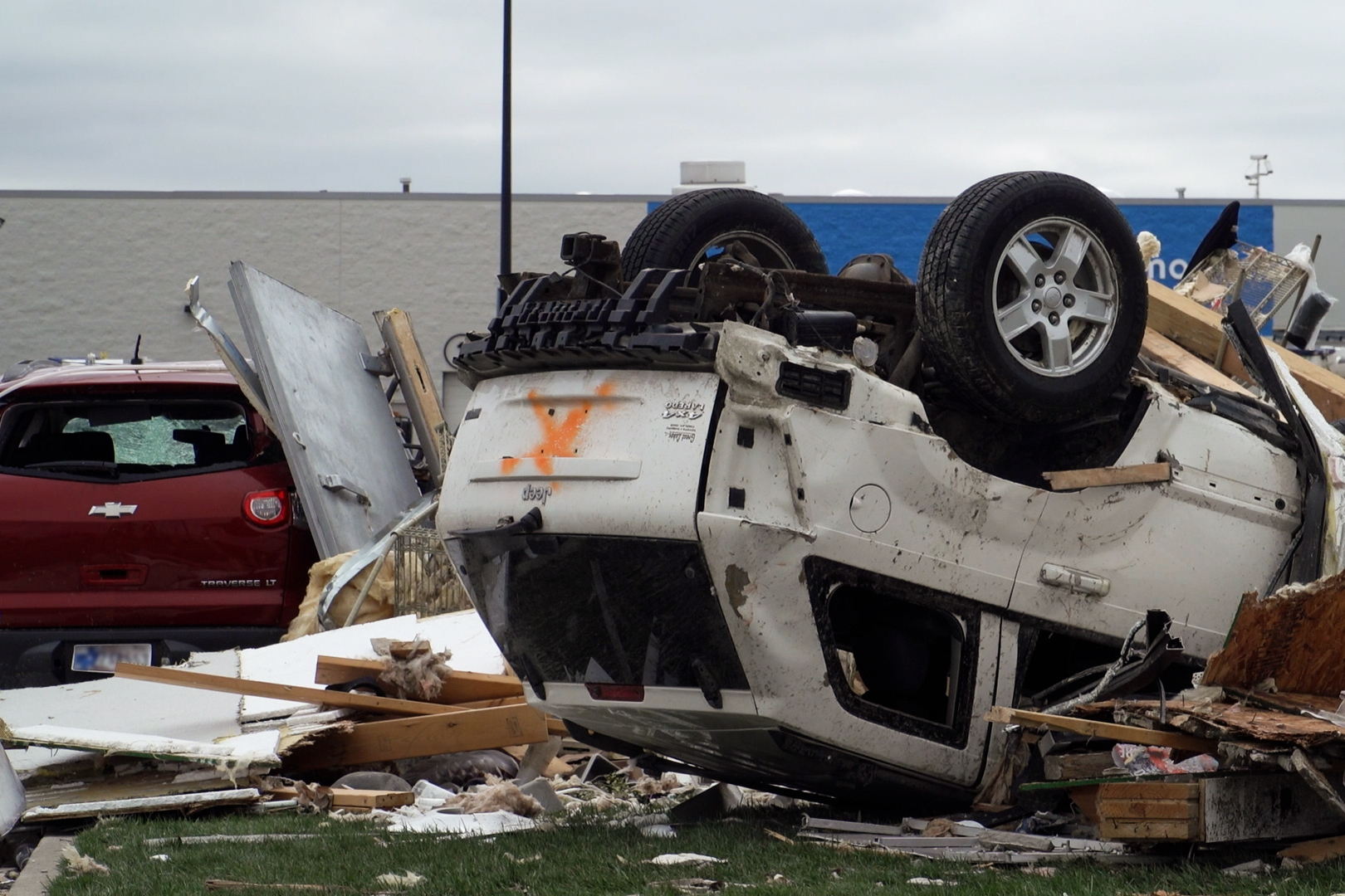 Two damaged vehicles and a pile of debris sits where a Taco Bell once was. The visible license plate has been blurred for privacy.